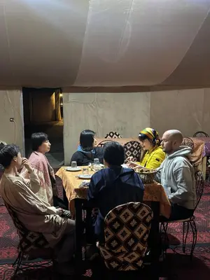 a group of people sitting around a table in a room at Sahara Joy Camp in Merzouga