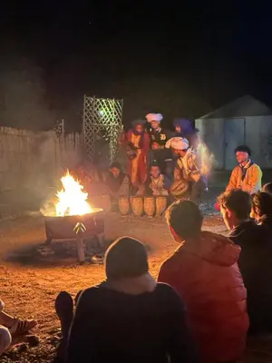 a group of people sitting around a fire at night at Sahara Joy Camp in Merzouga