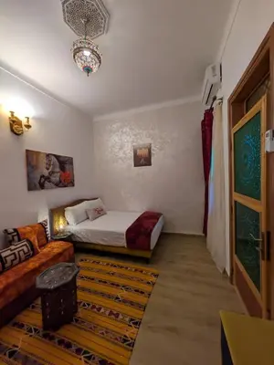 a bedroom with a bed and a couch and a chandelier at Apartment Amoud with a panoramic view in Fès