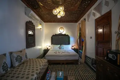 a bedroom with a bed and a couch and a chandelier at Dar Borj in Fès