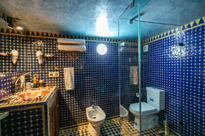 a blue tiled bathroom with a toilet and a sink at Dar Borj in Fès