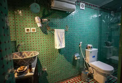 a green tiled bathroom with a toilet and a sink at Dar Borj in Fès