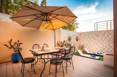 a patio with a table and chairs and an umbrella at Villa Perle 6 Suites with Pool 5 Min from Center in Oulad Akkou