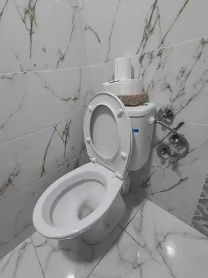 a white toilet in a bathroom with marble walls at Cozy GenYcool Apartment Meknes Center in Meknès
