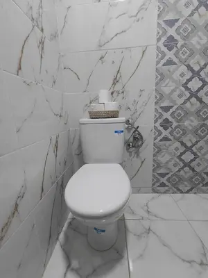 a white toilet in a bathroom with marble walls at Cozy GenYcool Apartment Meknes Center in Meknès