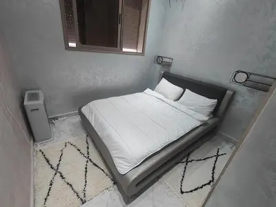 a small bed with white sheets and pillows in a room at Cozy GenYcool Apartment Meknes Center in Meknès