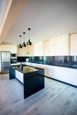 a large kitchen with white cabinets and a black island at Jnane Moulana Piscine Privée, Jardin & Vue Atlas