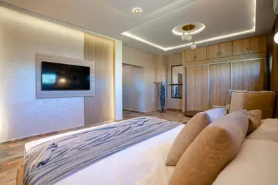 a bedroom with a large bed with a tv on the wall at Jnane Moulana Piscine Privée, Jardin & Vue Atlas