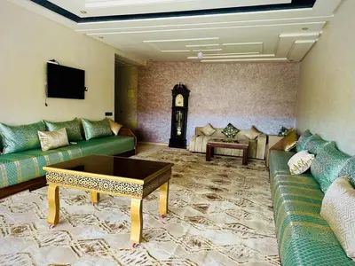 a living room with green couches and a clock at إقامة حسن in Fès