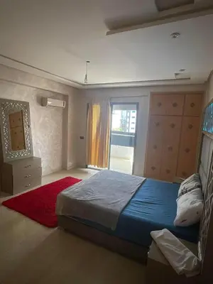 a bedroom with a bed with a red rug and a window at إقامة حسن in Fès