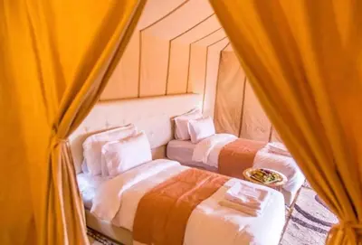 two beds in a room with curtains at Sahara Luxury Camp in Merzouga