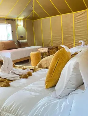 a room with a bunch of beds in a tent at Sahara Luxury Camp in Merzouga