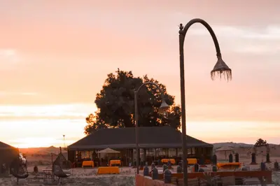 a street light in front of a building with the sunset at Maria'S Luxury Camp in Merzouga