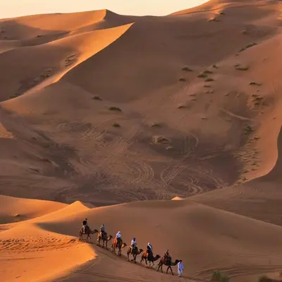 a group of people riding horses through the desert at Dream Land Camp in Merzouga