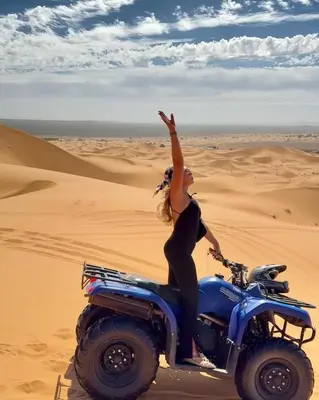 a woman riding a motorcycle in the desert at Dream Land Camp in Merzouga