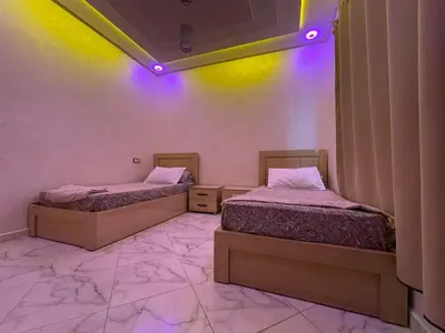 two beds in a room with purple lights at Air-conditioned apartment Atlas star in Azrou