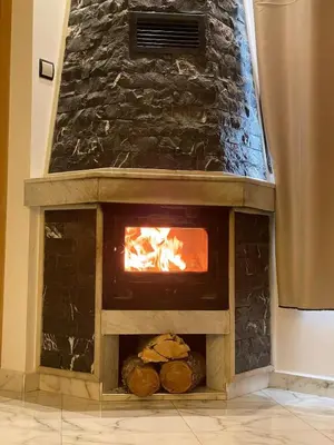 a stone fireplace with a fire in it at Air-conditioned apartment Atlas star in Azrou