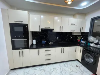 a kitchen with white cabinets and black appliances at Air-conditioned apartment Atlas star in Azrou