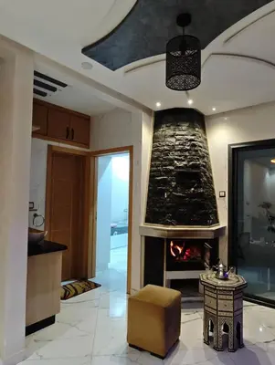 a living room with a fireplace and a table at Air-conditioned apartment Atlas star in Azrou