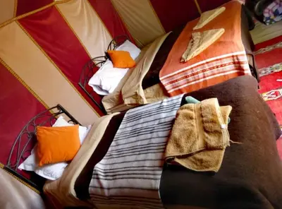 two beds in a tent with blankets and pillows at Chebbi Desert Camp in Merzouga