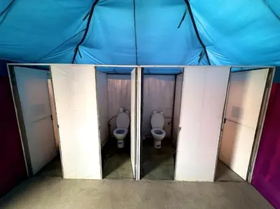 a group of three stalls with two toilets in a room at Chebbi Desert Camp in Merzouga