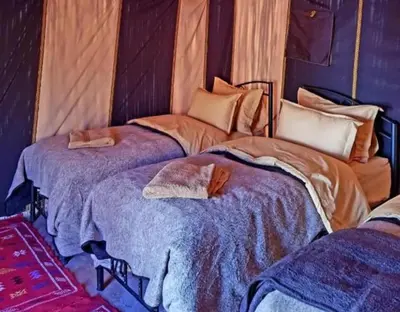 two twin beds in a room withermottermott at Chebbi Desert Camp in Merzouga