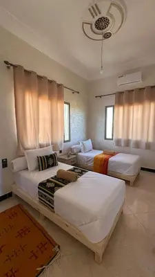 two beds in a room with windows and curtains at Apartment with Pool & Kasbah View in Aït Ben Haddou