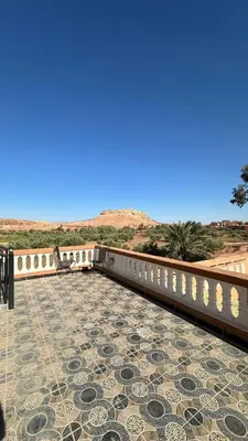 a person sitting on a bench on a patio at Apartment with Pool & Kasbah View in Aït Ben Haddou