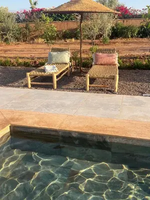 two chairs and an umbrella next to a swimming pool at Luxury VILLA - Pool-view Atlas-Ourika-Golfs in Akkara