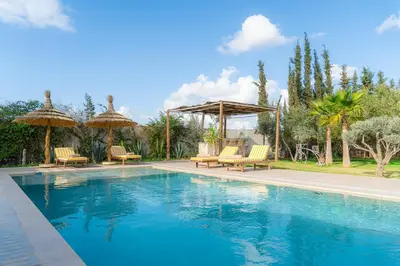 a swimming pool with chairs and umbrellas in a yard at Maison soli Marrakech