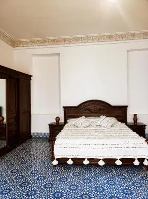 a bedroom with a bed with a blue patterned floor at Riad Benkirane in Fès