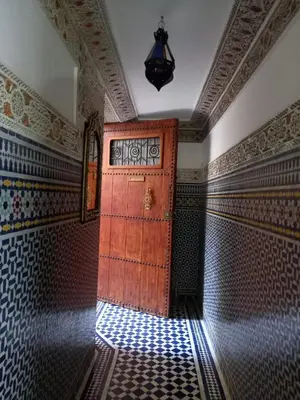a large wooden door in a room with patterns on the walls at Riad Benkirane in Fès