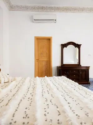 a bedroom with a large bed with a dresser and a mirror at Riad Benkirane in Fès