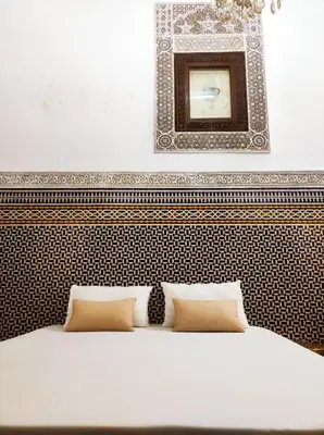 a bed with two pillows and a mirror above it at Riad Benkirane in Fès