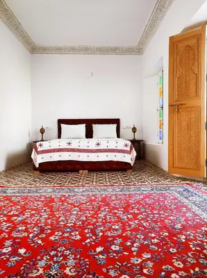 a bedroom with a bed and a red rug at Riad Benkirane in Fès