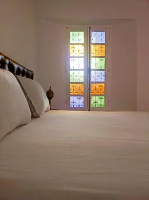 a bedroom with a white bed and two windows at Riad Benkirane in Fès