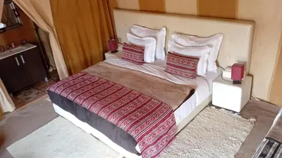 a bedroom with a large bed with red and white pillows at Mirage Luxury Camp in Merzouga
