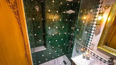a bathroom with a shower with a green tiled wall at Dar Magic Fes in Fès