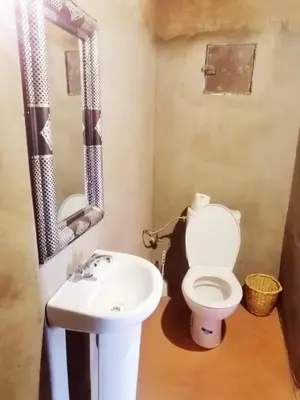 a bathroom with a white toilet and a sink at Tarrast Desert Camp in Mhamid