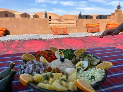 a plate of food on a table in the desert at Tarrast Desert Camp in Mhamid