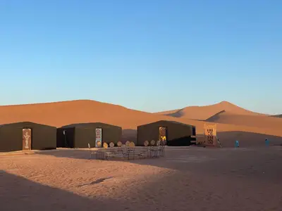 a group of tents in the middle of a desert at Tarrast Desert Camp in Mhamid
