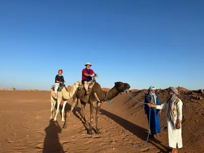 a group of people on camels in the desert at Tarrast Desert Camp in Mhamid