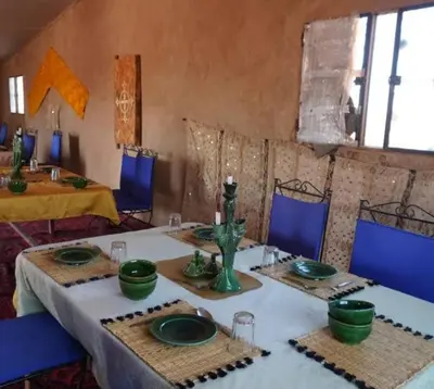 a dining room with two tables with green plates at Excursion Erg chegaga in Mhamid