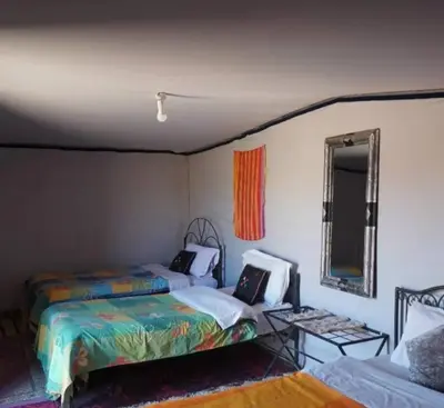 a bedroom with two beds and a mirror at Excursion Erg chegaga in Mhamid