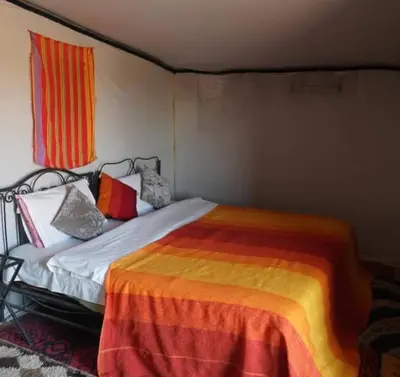 a bedroom with a bed with colorful sheets and pillows at Excursion Erg chegaga in Mhamid
