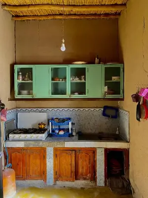 a kitchen with green cabinets and a counter top at Merzouga Desert Family Host tata- Hassi Labied Dunes View & Tours in Hassilabied