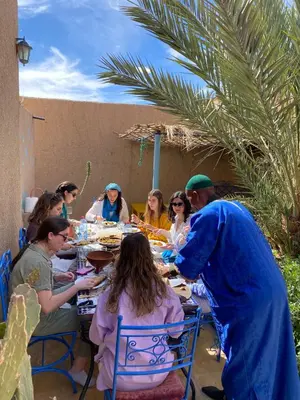 a group of people sitting around a table eating at Merzouga Desert Family Host tata- Hassi Labied Dunes View & Tours in Hassilabied