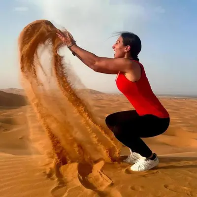 a woman in the desert playing in the sand at Africa Berber Camp in Merzouga