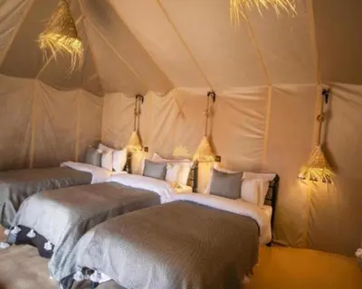 a group of four beds in a tent at Africa Berber Camp in Merzouga