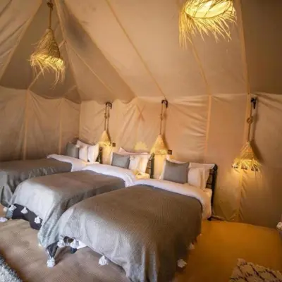 a group of four beds in a tent at Africa Berber Camp in Merzouga